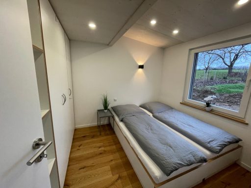 Helles, modernes Schlafzimmer mit zwei Betten und großer Fensteransicht.